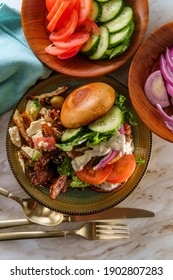 Greek Stuffed Turkey Burger Topped With Cucumber Slices And Tzatziki Yogurt Sauce Served With Mediterranean Street Cart Fried Potatoes With Feta Cheese Olives Herbs And Spices