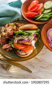 Greek Stuffed Turkey Burger Topped With Cucumber Slices And Tzatziki Yogurt Sauce Served With Mediterranean Street Cart Fried Potatoes With Feta Cheese Olives Herbs And Spices