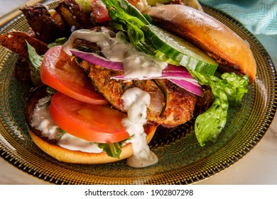 Greek Stuffed Turkey Burger Topped With Cucumber Slices And Tzatziki Yogurt Sauce Served With Mediterranean Street Cart Fried Potatoes With Feta Cheese Olives Herbs And Spices