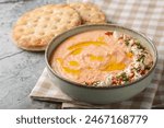 Greek Tirokafteri spread is a  spicy feta dip with feta cheese, roasted red peppers, garlic and chilli closeup on the bowl on the table. Horizontal
