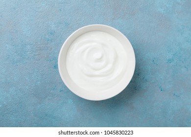 Greek Yogurt In Bowl On Blue Stone Table Top View.