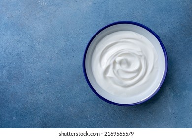 Greek Yogurt In Bowl On Blue Stone Table Top View.