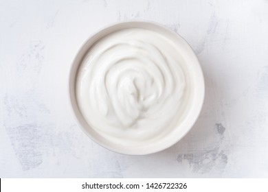 Greek Yogurt In Bowl On White Stone Table Top View.