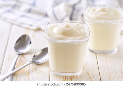 greek yogurt in a glass jars with spoons on a white table, selective focus.