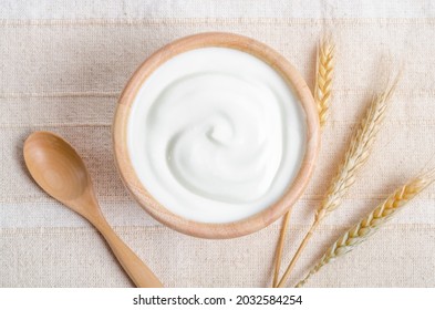 Greek yogurt in a wooden bowl and dry barley on tablecloth. - Powered by Shutterstock