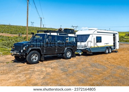 Green 4WD SUV with roof rack towing a large double axle caravan parked at a rest spot in south Africa