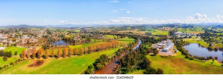 Green agriculture fields around Bega town and chees factory on Bega river in scenic valley - aerial panorama.