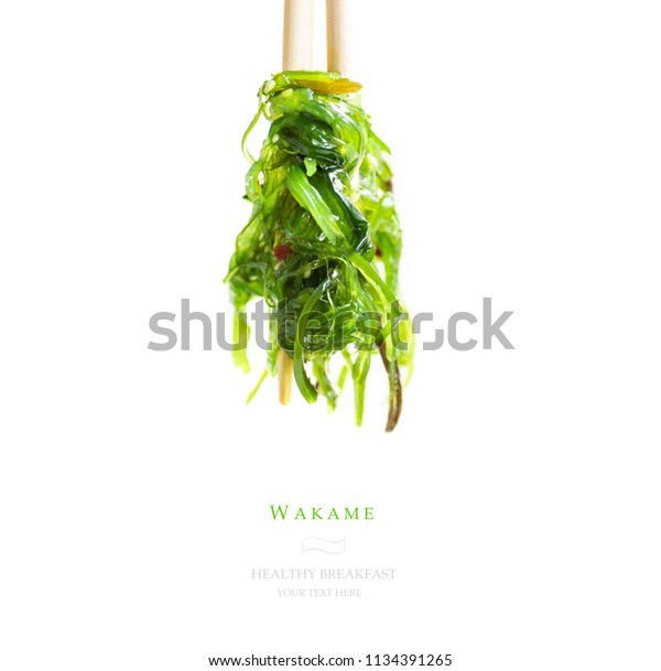Green algae salad on\
white isolated background. Hiyashi wakame. Wakame salad with\
chopsticks for sushi. 