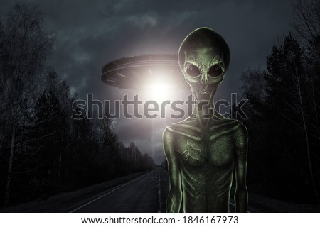 Green alien with black large glass eyes on the background of a flying saucer. UFO concept, aliens, contact with extraterrestrial civilization.