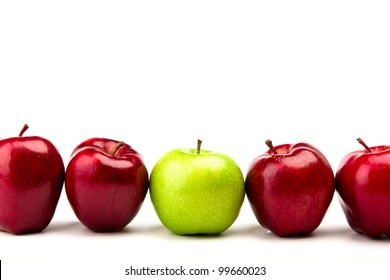 Green Apple Among Red Apples Isolated On A White