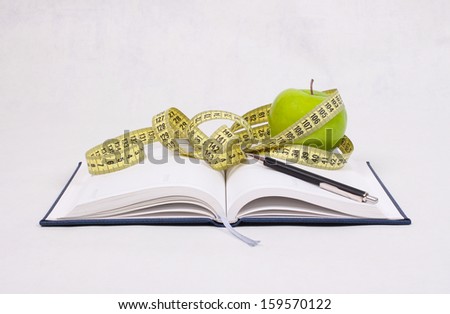 green apple and centimeter lie on a notepad