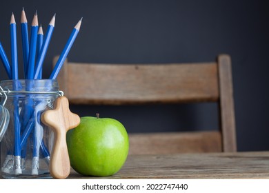 Green Apple, Christian Cross And Jar Of Pencils On Wood School Desk With Black Background