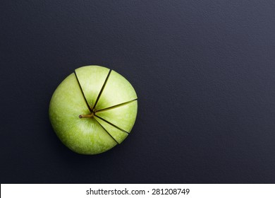 green apple cutting in the shape of pie chart on back board 