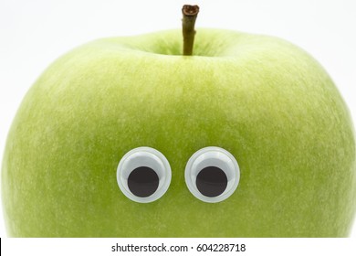 green apple with googly eyes on white background - portrait