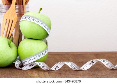 the green apple with Measuring tape on wooden background in concept of healthy and diet