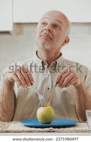 green apple sits before an old man who's poised to eat. Using utensils and making comical expressions, he secretly loathes his diet, longing for tasty, high-fat, and sugary foods. Yet, the medical war
