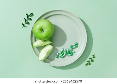 Green apple slices and a handful of capsules are displayed on ceramic dish. Flat lay. Vacant space on the dish for natural beauty cosmetic product advertising - Powered by Shutterstock