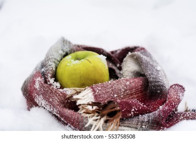 Green Apple Wrapped With Scarf In The Snow .Winter Time