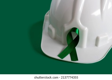 Green April, month of awareness about the importance of safety at work. Green ribbon and white hardhat