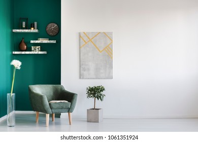 Green armchair between dandelion and plant in living room interior with copy space and grey painting - Shutterstock ID 1061351924