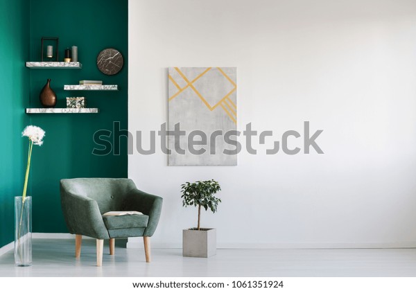 蒲公英和植物之间的绿色扶手椅在客厅内部与复制空间和灰色绘画库存照片 立即编辑