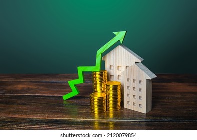 Green arrow up over wooden houses. Increasing cost of housing concept. High demand for real estate. Growth of mortgage rates. Sale apartments. Price increase. Maintenance cost. Raising property taxes