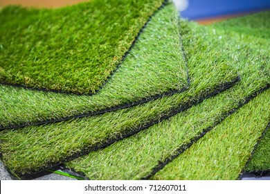 Green artificial turf rolled. Probes examples of artificial turf, floor coverings for playgrounds.