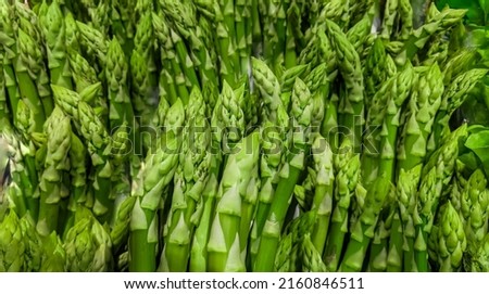 green Asparagus bunch on grocery market. Vegetable crisper full of green ripe raw sprouts. Healthy organic food