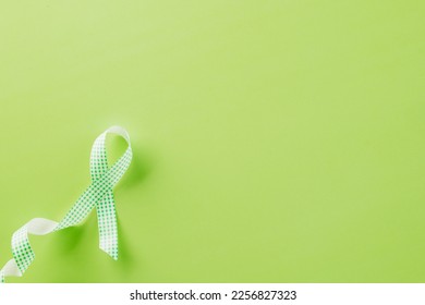 Green awareness ribbon of Gallbladder and Bile Duct Cancer month isolated on green background with copy space, concept of medical and health care support - Shutterstock ID 2256827323