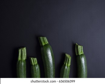Green baby zucchinis isolated on black background