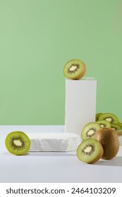 Green background features some halves of kiwi fruit with two podiums in white color. Kiwi skin is edible and contains key nutrients. Empty podium to show your product that extracted from Kiwi