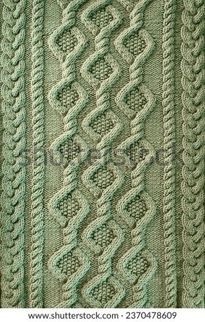 green background knitted fabric with a pattern. Knitted Arans close-up