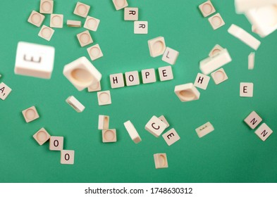 green background with scrabble pieces with the word hope and pieces falling