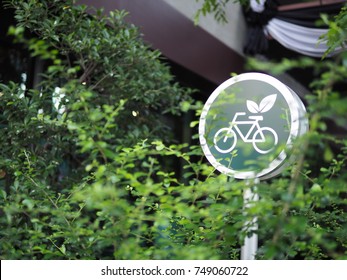 A Green Background Sign With White Bicycle And Leaf With White Round Margin In Front Of The Green Environment Of Tree And Leaf In The Garden In Big City