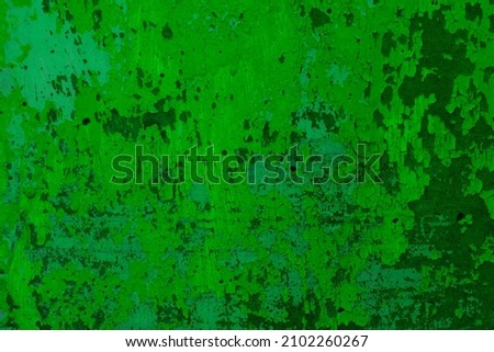 Green background of the wall with peeling paint and cracked plaster. Dark green grunge background.