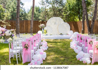 Green Backyard Decorated With Pink Balloons And Flowers Around Chairs And Wedding Altar