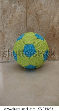 A green ball with a blue hexagonal pattern is on the floor