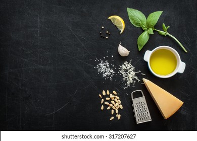 Green basil pesto - italian recipe ingredients on black chalkboard background from above. Parmesan cheese, basil leaves, pine nuts, olive oil, garlic, salt and pepper. Layout with free text space. - Powered by Shutterstock