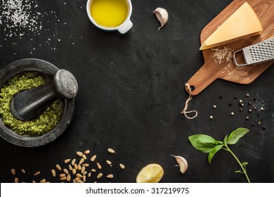 Green basil pesto - italian recipe ingredients on black chalkboard from above. Parmesan cheese, basil leaves, pine nuts, olive oil, garlic, salt, pepper and mortar. Layout with free text space. - Powered by Shutterstock