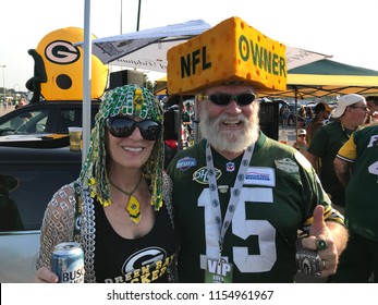Green Bay, Wisconsin. August 9th, 2018. Packer fans during at tailgate party at Lambeau Field. The man wears a cheesehead that says NFL Owner. The Packers are the only publicly owned NFL team.
