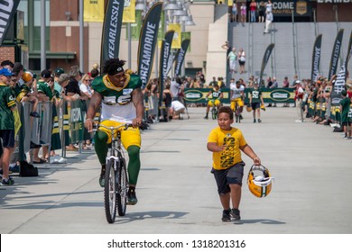 Green Bay, Wisconsin / USA - August 12, 2018: Packer players riding kid's bike to Packers Training Camp practice from Lambeau Field to Ray Nitschke Field