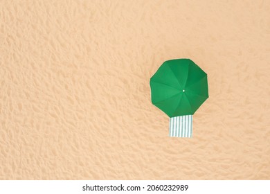 Green Beach Umbrella And Towel On Sandy Coast, Aerial View. Space For Text