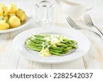 green bean with cream sauce and boiled potatoes on white table, selective focus.
Summer vegan dinner or snack.