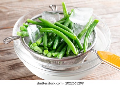 Green beans in a colander. Boiled or blanched vegetables on a wooden table - Shutterstock ID 2022663299