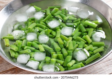 Green beans in a colander. Boiled or blanched vegetables in ice water on a wooden table - Shutterstock ID 2075446273