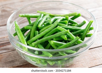 Green beans in glass bowl on a wooden table