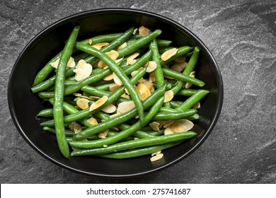 Green Beans With Toasted Almonds, In Black Bowl Over Dark Slate.  Overhead View.