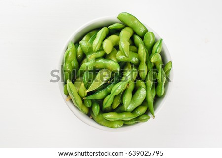 Green beans in a white bowl isolated on a white background. Top view