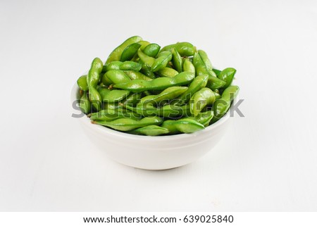 Green beans in a white bowl isolated on a white background. Top view