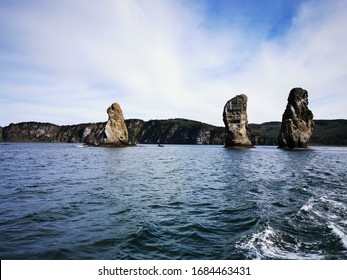 Green beautiful rocks of Kamchatka against the background of the bright blue sky. The edge of volcanoes. Rock Three brothers. Boat trip on a yacht with fishing. Petropavlovsk-Kamchatsky. Avacha Bay. R